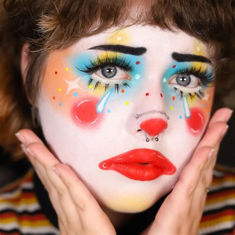 A close-up of various clown makeup products, highlighting the vibrant colors of the makeup crayons and the texture of the white face paint.