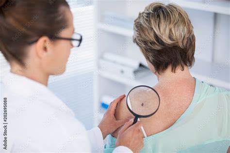 Dermatologist examining a mole on a patient's arm