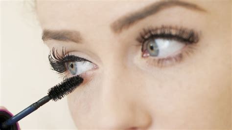 Split image: One side shows a person applying mascara, the other shows a close-up of perfectly defined, fanned-out lashes.
