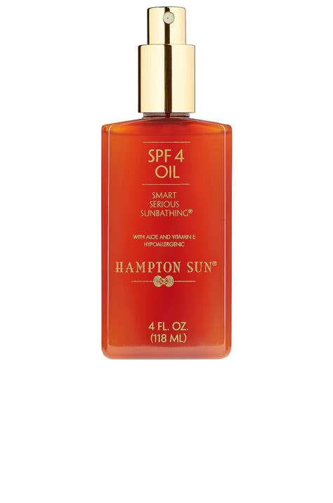 Aesthetic bottle of Hampton Sun SPF 4 Oil with a sandy background and a hint of tropical foliage.