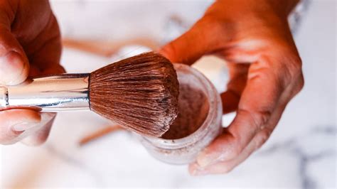 Close-up of a makeup artist blending bronzer on the cheekbones with a brush for a sculpted effect.