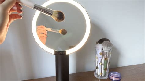 Close-up of a makeup artist using a lighted mirror for precise application