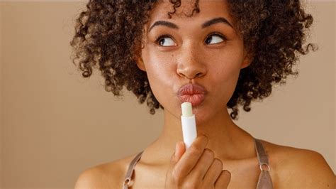 Close-up of a person applying a balm to their face.