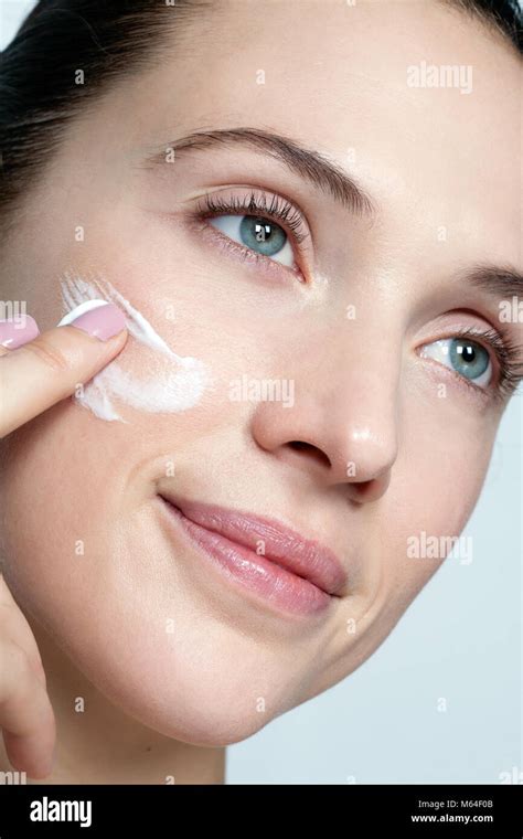 Close-up of a woman applying face cream, showcasing a gentle shimmering effect on her hands.