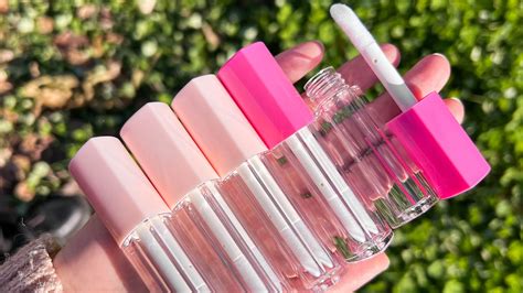 Close-up of a hand holding an open lip gloss tube with a built-in LED light illuminating the applicator.