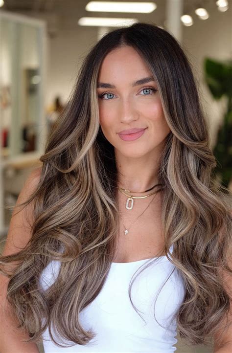 A person with brown skin showing off subtle blonde highlights that add dimension to their hair.