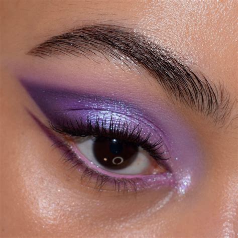 A model with brown eyes demonstrating a soft purple eyeshadow look with a subtle winged eyeliner.