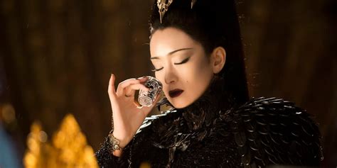 A close-up of Gong Li's face in Mulan, showcasing the intricate white mask and hawk-inspired eye makeup.