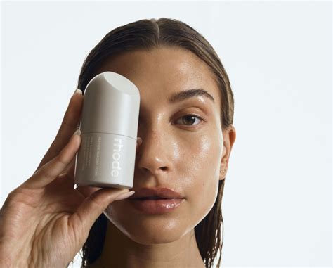 Hailey Bieber holding a Rhode skincare bottle, hinting at a new product launch.