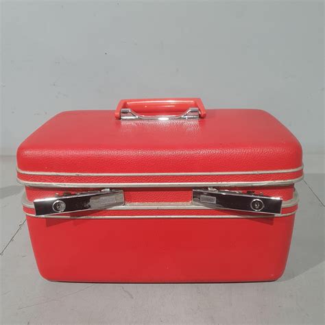 A vintage train case with a vibrant red lining, used for decor and storage.