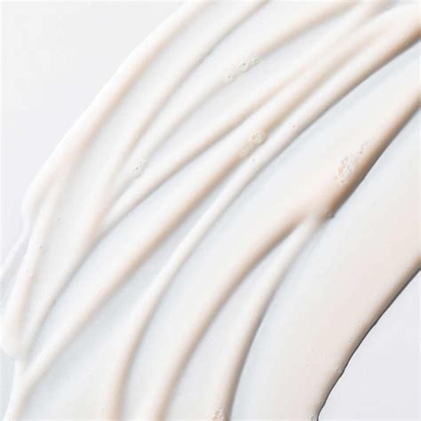 Close-up of a white, creamy facial cleanser with a gentle lather, highlighting its texture.