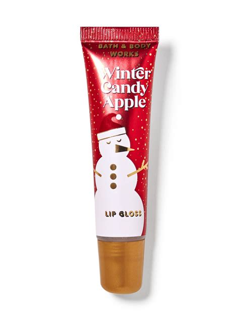 A close-up of the Winter Candy Apple lip gloss tube, showing its festive packaging and glossy finish.