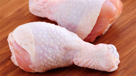 Close-up of a raw chicken leg showing dark spots at the end of the bone.