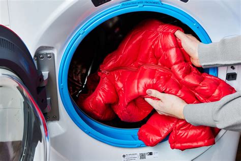 photo of a person carefully loading a down vest into a washing machine