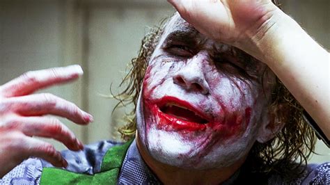 A close-up of Heath Ledger's Joker makeup, emphasizing the smeared white paint, black eye makeup, and red grin.