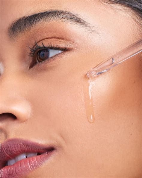 Close-up shot of a person applying a hyaluronic acid serum to their face.