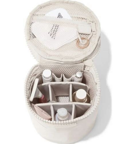 The Dagne Dover Mila Toiletry Organizer in a neutral color, showcasing its compact circular design and interior compartments.