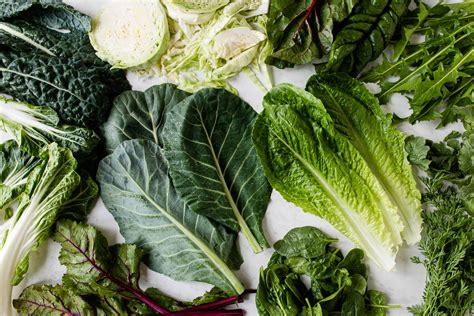 A selection of fresh fruits and leafy greens, including kale, spinach, pineapple, and banana, arranged artfully.