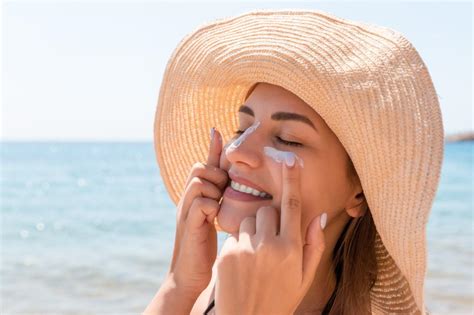 Image of a person applying sunscreen to their face, emphasizing sun protection.