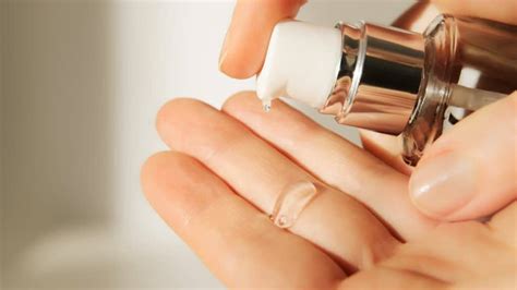 Close-up of a hand applying primer to the face with fingertips.