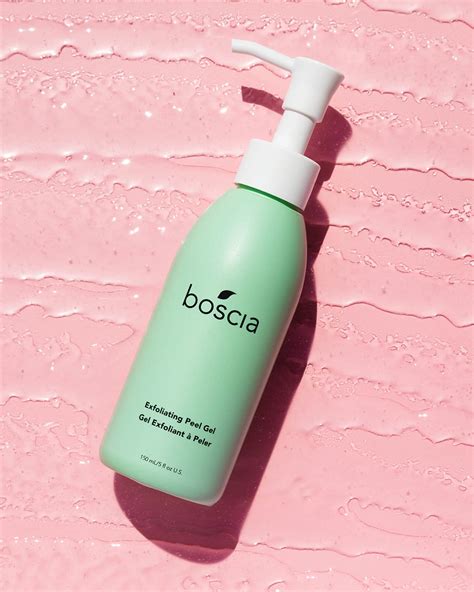 Close-up of hands demonstrating the peeling effect of Boscia Exfoliating Peel Gel, showing small white balls of dead skin.