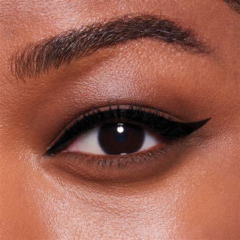 Eye makeup featuring a precise winged eyeliner with added small rhinestones at the outer corner.