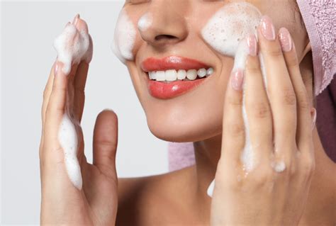 Close-up image of a foaming facial cleanser being dispensed onto a hand.