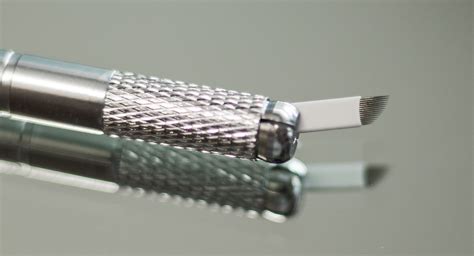 Close-up of various microblading needles and handheld tools.