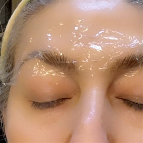 Illustration demonstrating the application of numbing cream and plastic wrap on eyebrows.