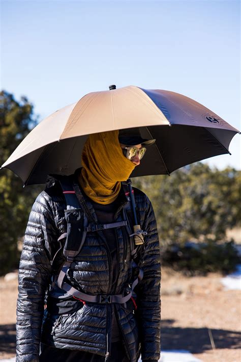 Image of a hiker using a trekking umbrella to create shade on a sunny trail.