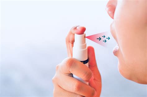 Photo of a person discreetly using a portable mouth spray while on the go.