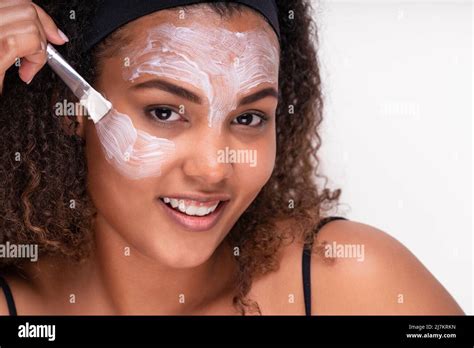A person applying a face mask with a brush.