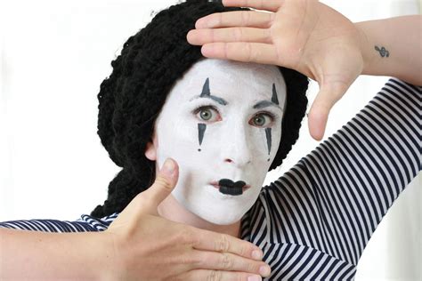 A mime artist applying white face paint