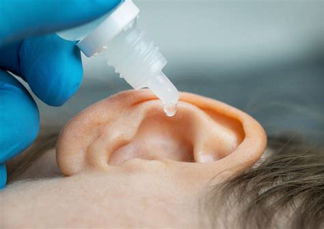 Diagram showing proper technique for applying emollient to the ear with a cotton bud.