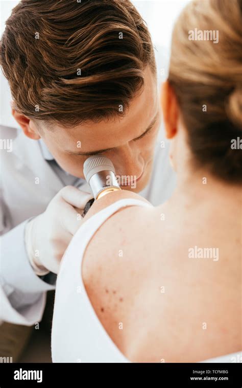 A dermatologist examining a patient's skin in a modern clinic setting.