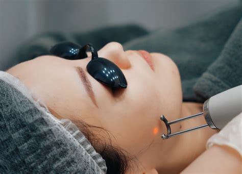 Close-up of a dermatologist's hand holding a Pico Laser device, ready to treat a patient's face.