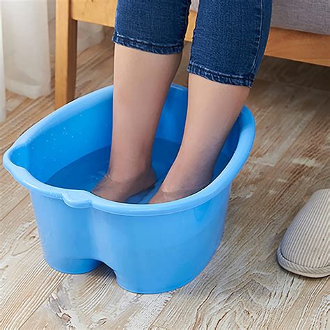 Person soaking their feet in a basin with mild bubbles, indicating a relaxing foot bath.