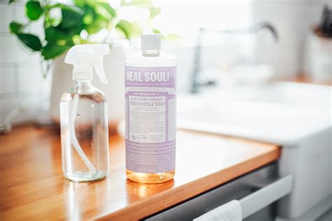 A clean kitchen counter with various cleaning supplies, featuring a bottle of castile soap.