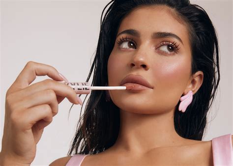 A makeup artist applying lipstick to Kylie Jenner, highlighting their collaborative process.