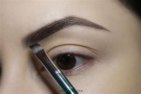 Close-up of a man's eyebrows being filled in with a brush and powder