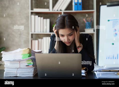 A person looking tired and overwhelmed at a desk, with a green smoothie in hand.