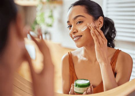A person applying moisturizer to their face, emphasizing hydration.