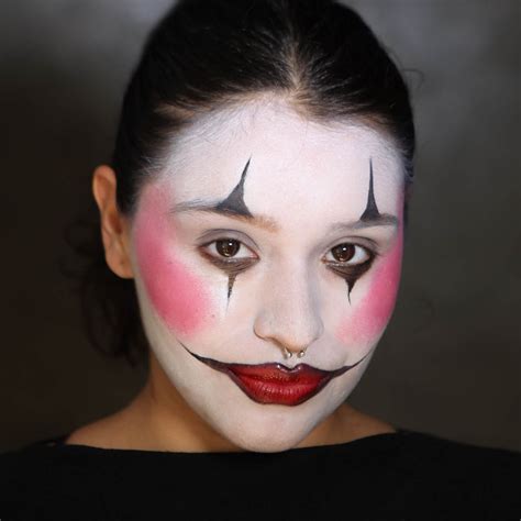 A person applying white clown makeup to their face
