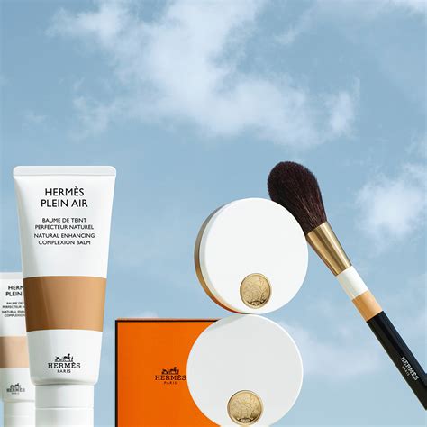 An assortment of Hermès beauty products, including complexion balms, lipsticks, and nail polishes, arranged artfully.
