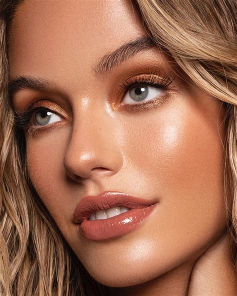 A model wearing burnt orange smoky eye makeup with bronzed skin and nude lipstick.