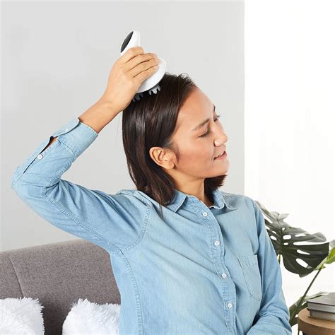 Image of a person gently massaging their scalp with a scalp massager.