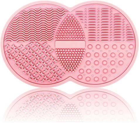 A makeup brush being swished on a textured cleaning pad, with soapy lather visible.