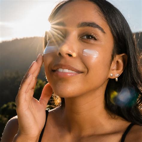 A woman applying moisturizer to her face