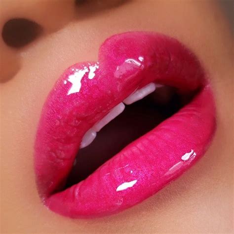 A close-up of lips with a bold, vibrant hot pink lipstick applied, demonstrating an intense color payoff.