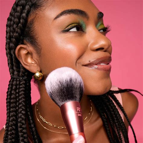 A makeup artist applying powder foundation with a large, dense brush.